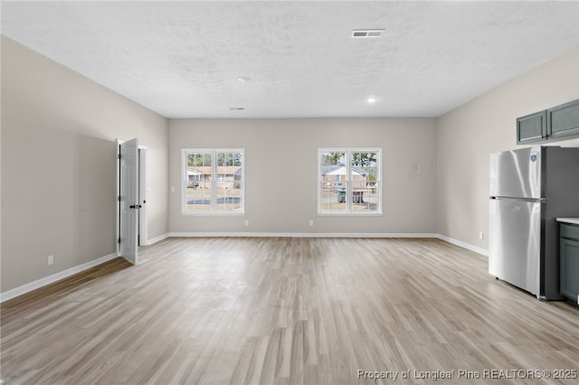 unfurnished living room featuring light hardwood / wood-style flooring and a textured ceiling