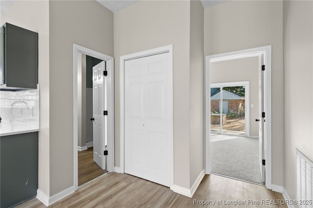 hall with sink, a high ceiling, and light wood-type flooring