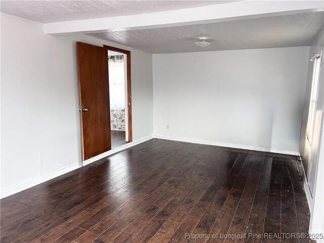 empty room with dark wood-type flooring and a textured ceiling