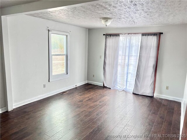 empty room with dark hardwood / wood-style flooring and a textured ceiling