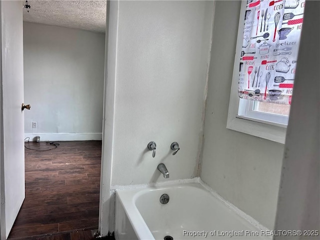 bathroom featuring wood-type flooring, a bath, and a textured ceiling