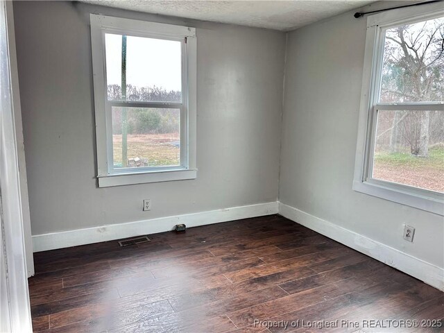 spare room with dark wood-type flooring and a textured ceiling