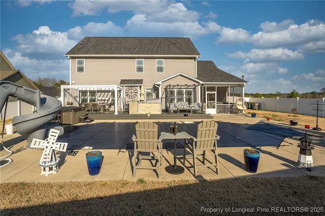 rear view of property featuring a hot tub, a patio, exterior bar, and a pergola