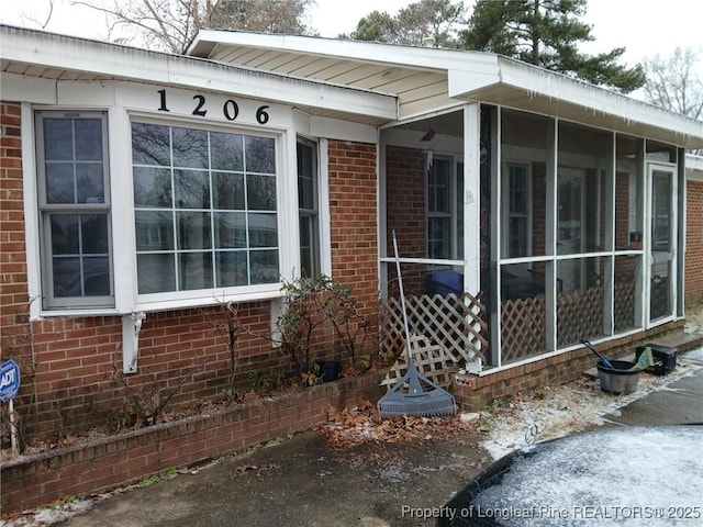 view of property exterior with brick siding and a sunroom