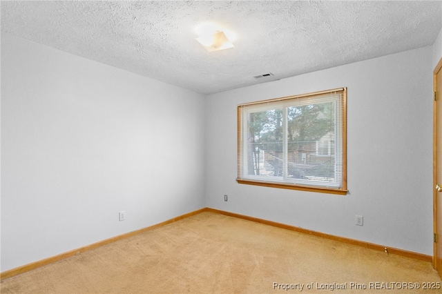 empty room featuring visible vents, light carpet, baseboards, and a textured ceiling