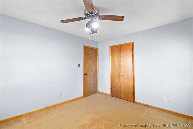 unfurnished bedroom with light carpet, ceiling fan, a closet, and baseboards