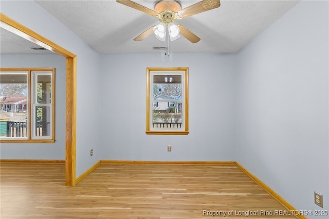 empty room featuring a healthy amount of sunlight, light wood-style floors, and visible vents