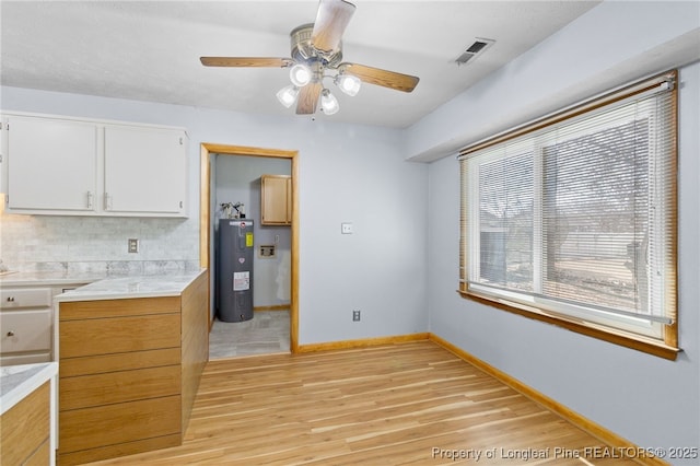 kitchen featuring light wood-style flooring, visible vents, white cabinetry, water heater, and light countertops