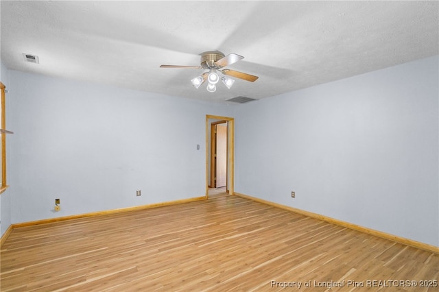 unfurnished room featuring light wood-style floors, visible vents, and baseboards