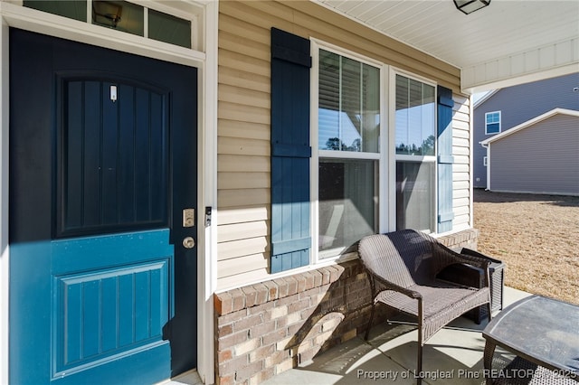 doorway to property featuring covered porch and brick siding