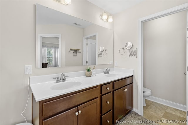 full bathroom featuring toilet, double vanity, a sink, and visible vents