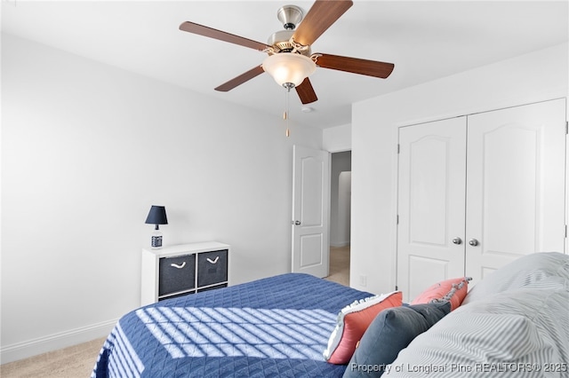 bedroom featuring a closet, light carpet, ceiling fan, and baseboards