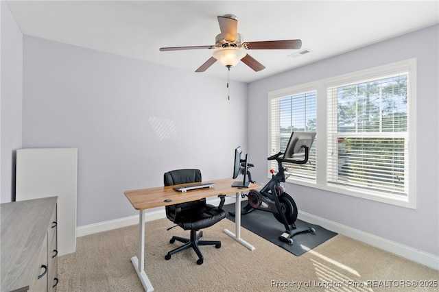 office space featuring light colored carpet, ceiling fan, visible vents, and baseboards