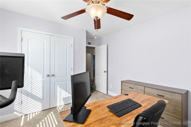 office area featuring baseboards, ceiling fan, and light colored carpet