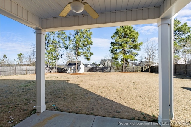 view of yard featuring a ceiling fan, a fenced backyard, an outdoor structure, and a shed