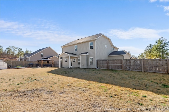 back of property featuring a fenced backyard, a lawn, and a gazebo