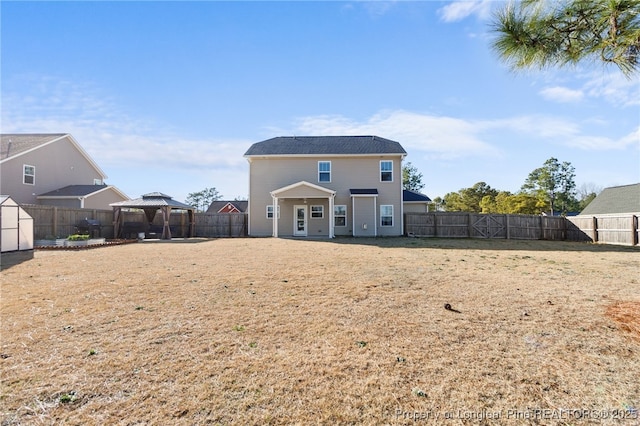 rear view of house with a fenced backyard, a lawn, and a gazebo