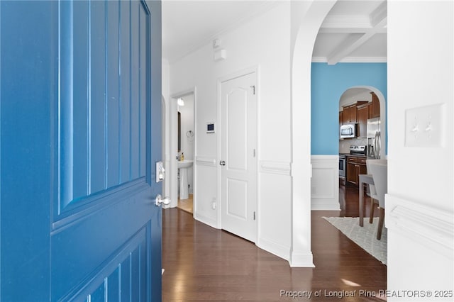 entrance foyer with arched walkways, beam ceiling, ornamental molding, dark wood-type flooring, and coffered ceiling