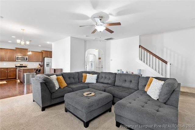 living room with recessed lighting, visible vents, arched walkways, stairs, and ceiling fan with notable chandelier