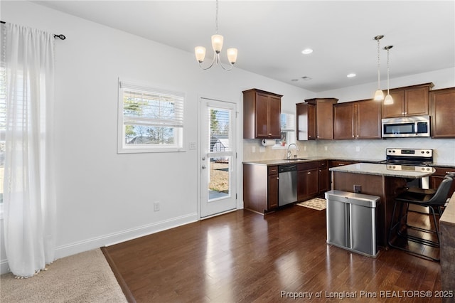 kitchen featuring hanging light fixtures, appliances with stainless steel finishes, a breakfast bar, and a center island