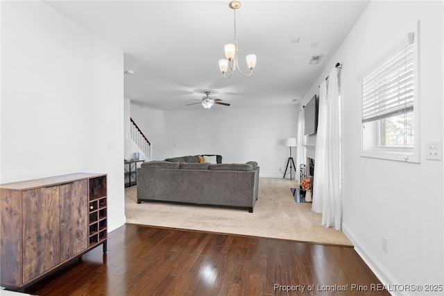 living room featuring stairs, ceiling fan with notable chandelier, a fireplace, and wood finished floors