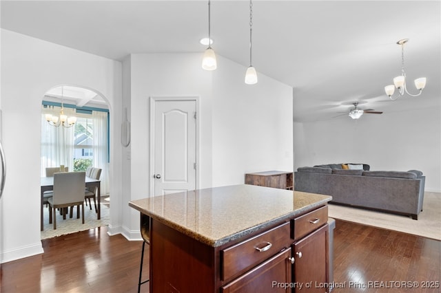 kitchen with dark wood-type flooring, a center island, open floor plan, and arched walkways