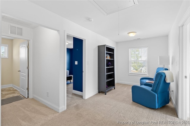 living area with visible vents, baseboards, attic access, and light colored carpet