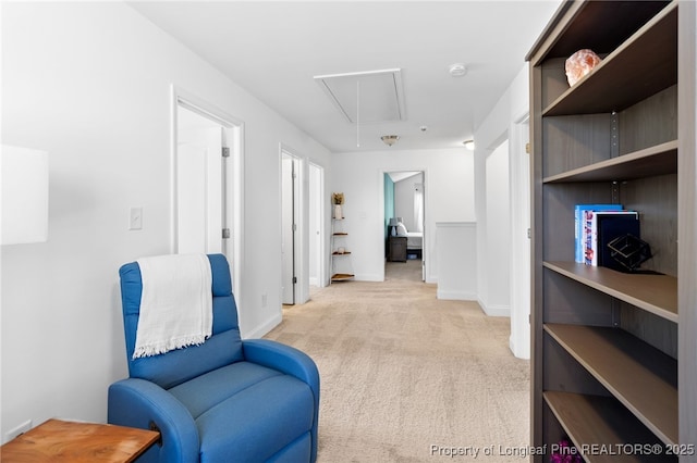 living area with light carpet, attic access, and baseboards