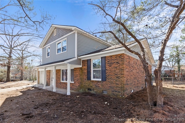 view of property exterior featuring brick siding, crawl space, a porch, and fence