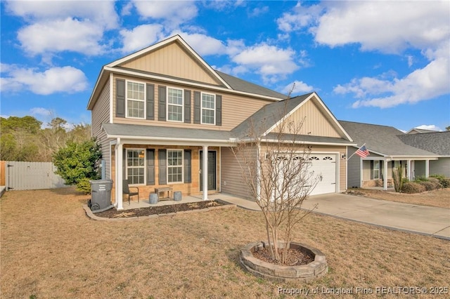 view of front of house featuring covered porch, concrete driveway, an attached garage, fence, and a front lawn