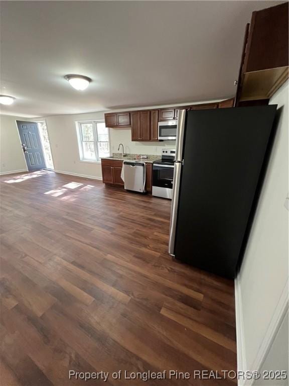 kitchen with baseboards, dark wood finished floors, stainless steel appliances, light countertops, and open floor plan