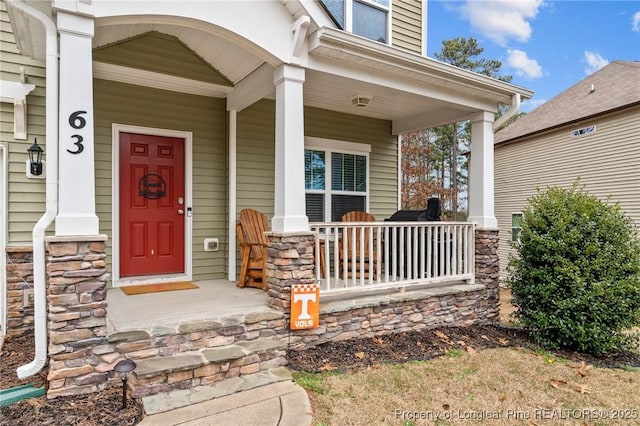 doorway to property with stone siding and covered porch