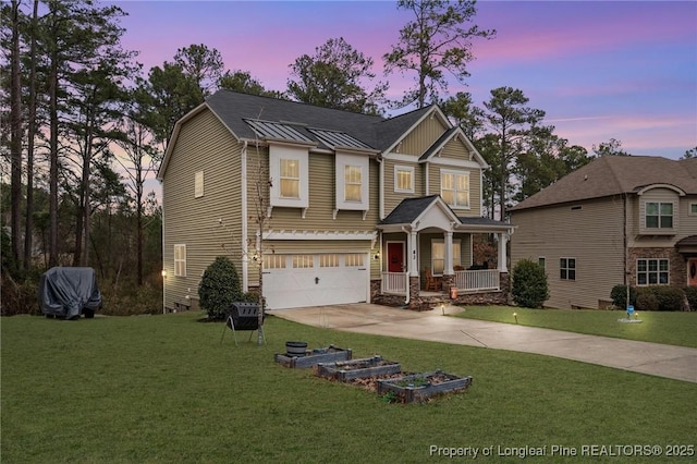 view of front of home featuring a standing seam roof, a front yard, covered porch, and driveway