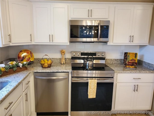 kitchen featuring white cabinetry, light stone counters, backsplash, and appliances with stainless steel finishes