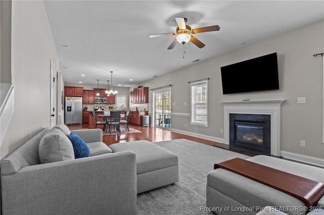 183 Ganton Dr, Raeford, NC 28376 - living area featuring baseboards, a fireplace with flush hearth, recessed lighting, ceiling fan with notable chandelier, and dark wood-style flooring