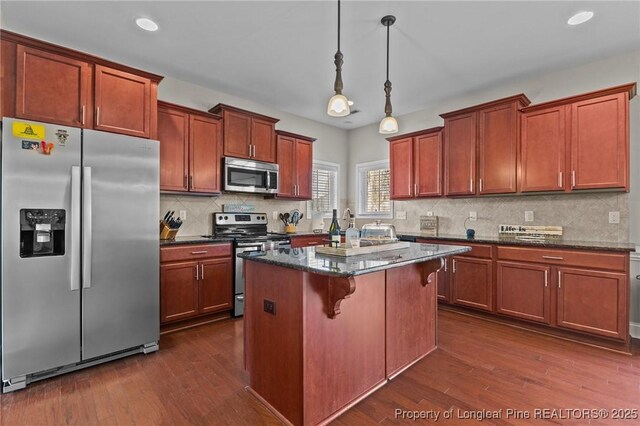 183 Ganton Dr, Raeford, NC 28376 - kitchen with dark wood-style floors, a kitchen island, stainless steel appliances, pendant lighting, and a kitchen breakfast bar