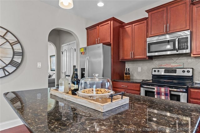 183 Ganton Dr, Raeford, NC 28376 - kitchen featuring dark stone counters, arched walkways, tasteful backsplash, and stainless steel appliances