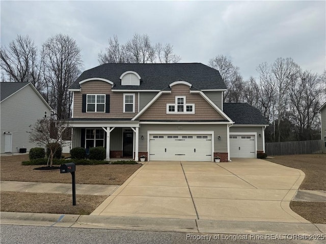 view of front of home with driveway, fence, covered porch, an attached garage, and a shingled roof