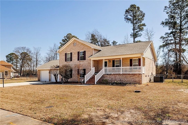 tri-level home featuring fence, driveway, a porch, a garage, and brick siding