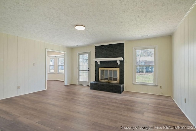 unfurnished living room featuring plenty of natural light, a fireplace, and wood finished floors