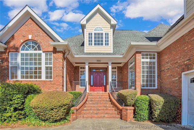 entrance to property featuring brick siding and a shingled roof