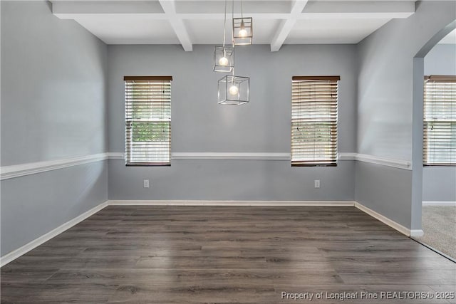 unfurnished dining area featuring arched walkways, beamed ceiling, baseboards, coffered ceiling, and dark wood-type flooring