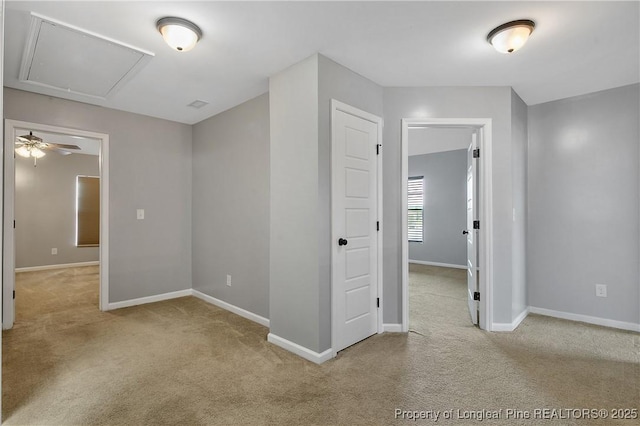 empty room featuring attic access, carpet flooring, baseboards, and ceiling fan