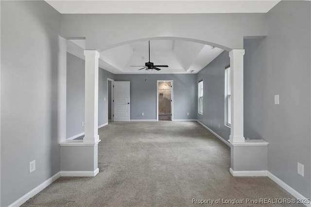 unfurnished living room featuring ornate columns, a ceiling fan, carpet, and a raised ceiling