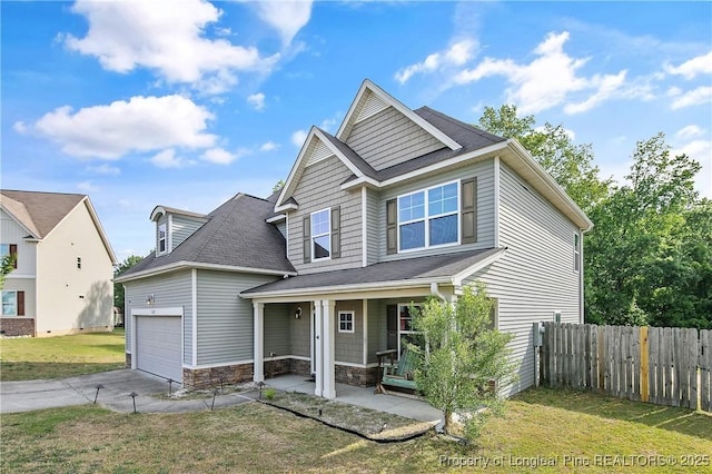 view of front of home with stone siding, covered porch, fence, a garage, and a front yard