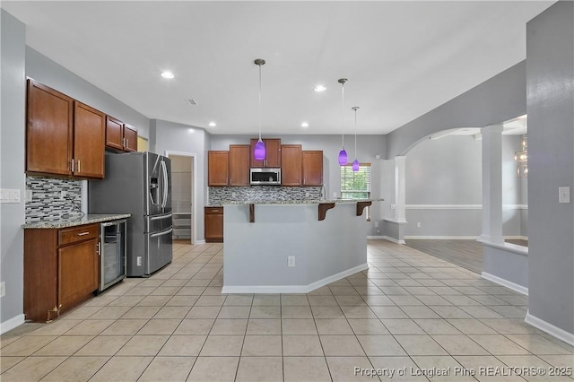 kitchen featuring backsplash, appliances with stainless steel finishes, a kitchen breakfast bar, and wine cooler