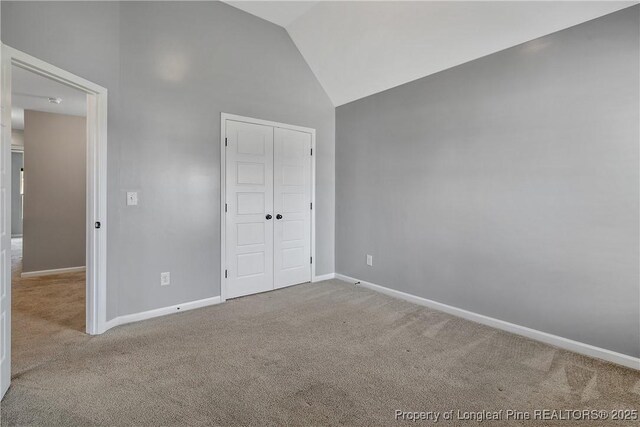 unfurnished bedroom with baseboards, carpet, a closet, and high vaulted ceiling