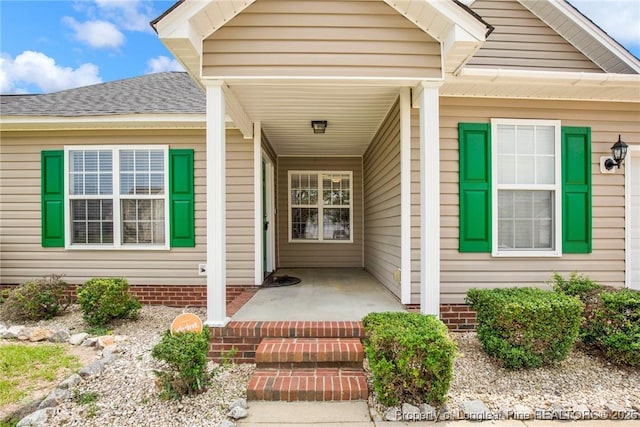 property entrance with a porch and roof with shingles