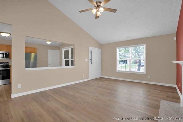 unfurnished living room featuring light wood-type flooring, a ceiling fan, high vaulted ceiling, and baseboards