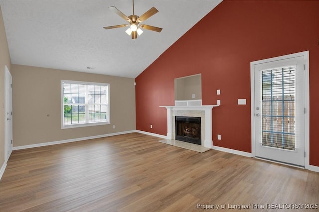 unfurnished living room featuring high vaulted ceiling, a ceiling fan, wood finished floors, a premium fireplace, and baseboards